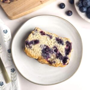 Slice of homemade blueberry bread with a golden crust and moist, fluffy interior, packed with fresh blueberries—perfect for breakfast or a sweet treat.