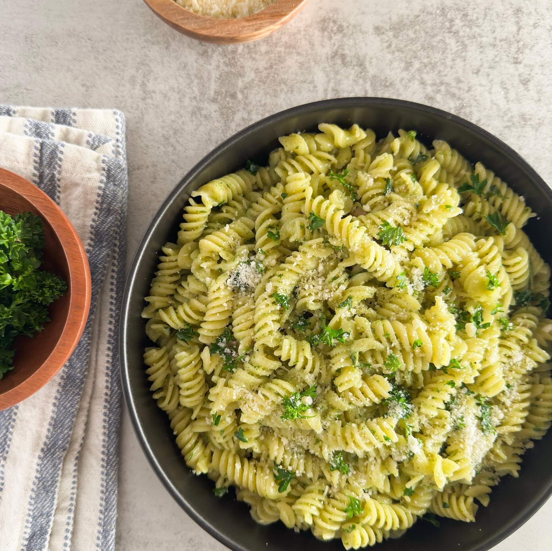 A plate of creamy pesto pasta coated in a rich, velvety sauce made with fresh basil, garlic, and parmesan—topped with extra cheese and herbs.